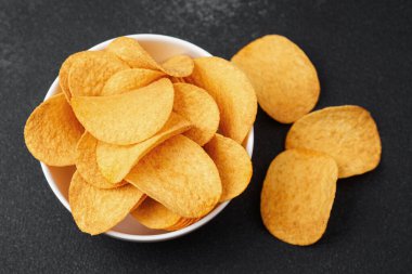 Altın, çıtır çıtır patates atıştırmalıkları toplanmak için karanlık bir yüzeyde bir kasede toplandı..