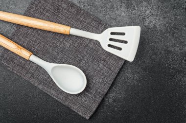 İki ahşap mutfak gereçleri koyu bir yüzey üzerinde dokulu keten havlunun yanında dinleniyor..