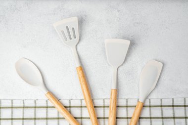 Çeşitli mutfak gereçleri damalı bir kumaşın yanında hafif bir yüzeye uzanır..