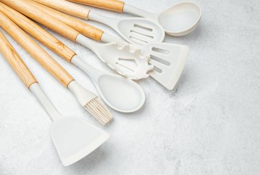 Ahşap saplı mutfak gereçleri pürüzsüz bir tezgahın üzerine serilmiş..