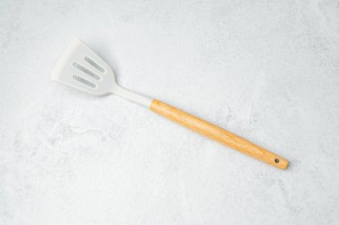 Katı bir spatula, açık gri mutfak tezgahında yemek pişirmeye hazır bekliyor..