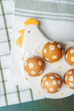 Elle boyanmış papatya yumurtalarının tavuklu Paskalya tabağında üst görüntüsü. 