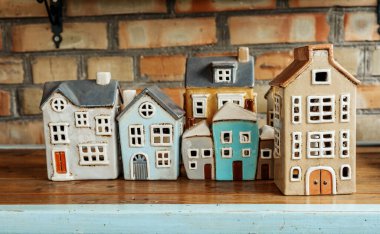 Renkli seramik evler tuğla bir duvara karşı kırsal bir ahşap masada sergilenir..