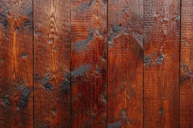 Yıpranmış tahtaların yakın plan çekimleri zengin dokuları ve koyu renkleri vurguluyor