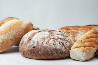 Tarafsız bir zemine yerleştirilmiş çeşitli taze ekmek türleri.