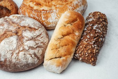 Açık bir yüzeyde çeşitli taze pişmiş ekmek türleri sergilenmektedir..