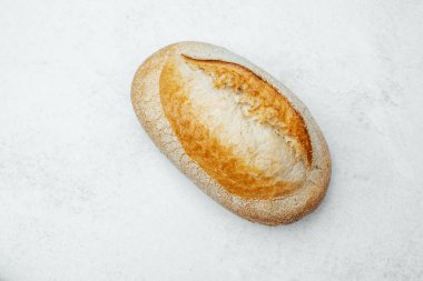 Hafif mermer yüzeyde duran lezzetli kabuklu ekmek, dokusunu sergiliyor..