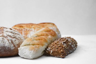Basit beyaz bir arkaplanda gösterilen çeşitli ekmek türleri, tazelik sergiliyor.