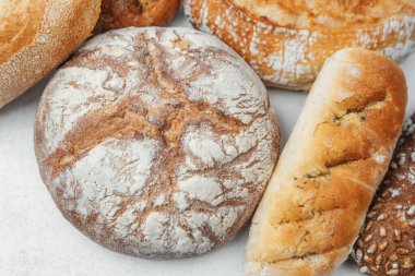 Beyaz taş bir yüzeye yerleştirilmiş çeşitli zanaatkar ekmek türleri.