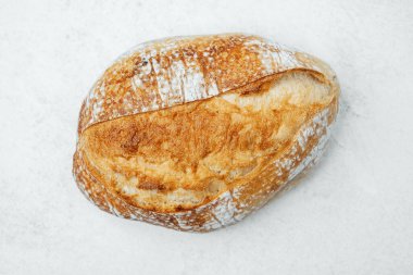 Kırsal ekşi ekmek, sıcak bir mutfak ortamında hafif bir yüzeye dayanır..