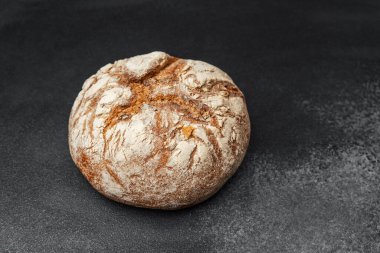 Esnaf ekmeği koyu bir yüzeyde oturur ve kabuğunu ve dokusunu gösterir..