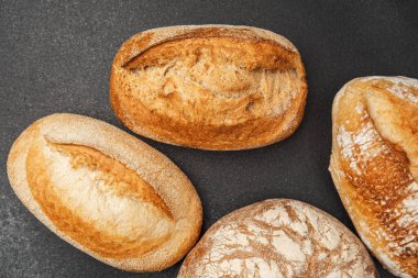 Dört ayrı somun güzel pişmiş ekmek, karanlık bir yüzeye dizilmiş..