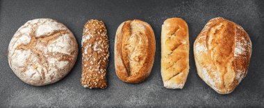 Çeşitli somun ekmekler kırsal bir zemin ile sıralanır, gösterişli dokular.