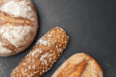 Üç çeşit zanaatkar ekmek, koyu renkli bir yüzey üzerinde güzelce sıralanmış..