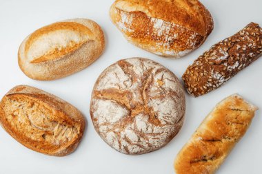 Çeşitli ekmek türleri taze pişmiş ve temiz bir yüzeyde sergileniyor..