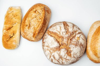 Temiz beyaz bir yüzeye sergilenen farklı taze ekmek türleri.