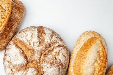 Açık bir yüzeyde üç çeşit ekmek sergilenir ve kabuklu dokuları sergilenir..