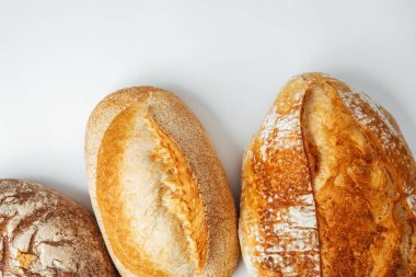 Üç farklı ekmek somunu kabuklu yüzeylerini ve dokularını gösterir..