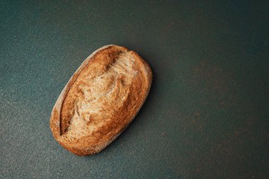 Esnaf ekmeğinin altın sarısı bir somunu koyu dokulu bir yüzeyde oturarak yaratıcılığı davet eder..