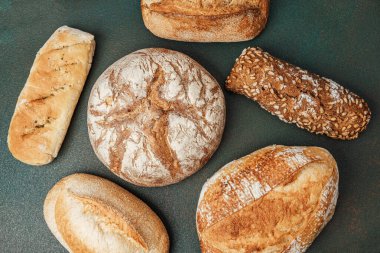 Koyu bir arkaplanda gösterilen farklı ekmek türleri koleksiyonu.