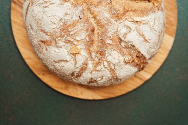 Mutfaktaki ahşap bir tahtanın üzerinde soğuyan yuvarlak bir somun ekmek..