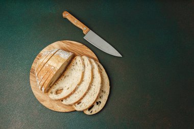 Tahtaya konmuş taze ekmek dilimleri ve yakınlarda bir mutfak bıçağı..