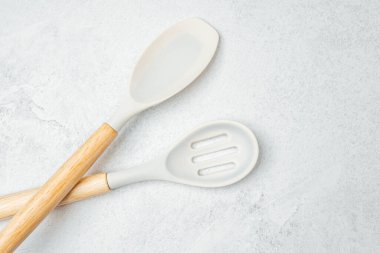 Ahşap saplı iki mutfak gereçleri düzgün, gri bir arka plana yerleştirilmiş..