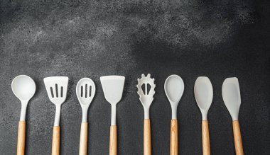 Karanlık bir yüzeyde düzenlenmiş çeşitli mutfak aletleri benzersiz tasarımlarını sergiliyor..