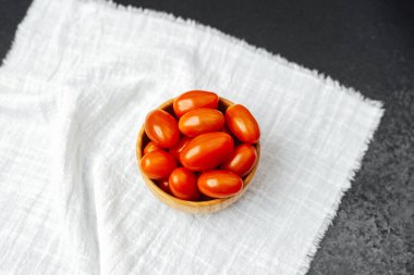 Renkli kiraz domatesleri yumuşak kumaş üzerinde ahşap bir kasede düzgünce düzenlenir..