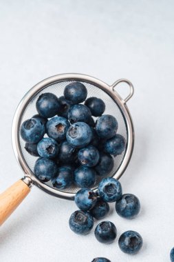 Hafif bir yüzeyde metal elek içinde dinlenen bir demet taze yaban mersini..