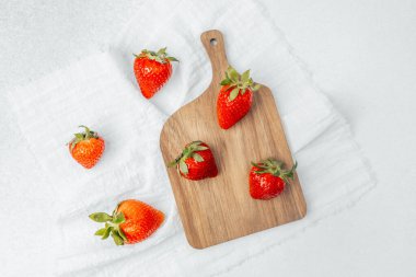 Tahta kesme tahtasında birkaç canlı çilek var..