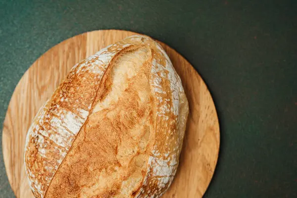 Güzel bir somun ekşi ekmek ahşap bir tahtanın üzerinde duruyor, eğlenmeye hazır..