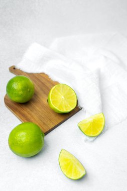 Misket limonları, yakınlarda beyaz bir bez parçasıyla tahta bir tahtanın üzerinde açılır..