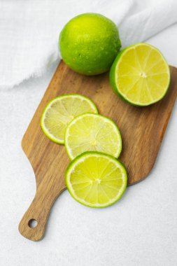 Limonlar ahşap bir kesme tahtasının üzerinde dilimlenir ve bütün limonlar yakınlarda sergilenir..