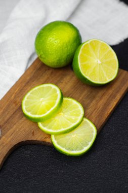 Parlak yeşil limonlar kullanıma hazır ahşap bir yüzey üzerinde ince dilimler halinde kesilmiş..