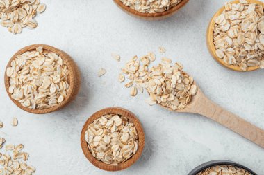 Hafif bir yüzeyde yulaf dolu çeşitli kaseler kırsal bir görünüm yaratıyor..