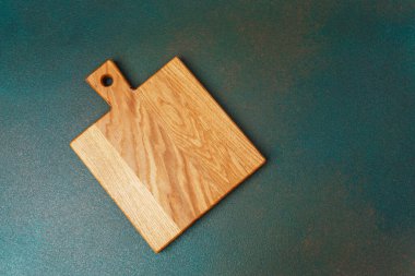 Tahta kesme tahtası yeşil bir yüzey üzerinde düz yatar ve doğal tahılını vurgular..