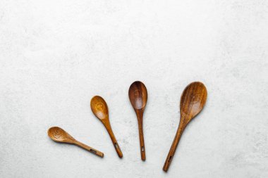 El yapımı ahşap kaşıklar, tarafsız bir arkaplana karşı sıraya dizilmiş..
