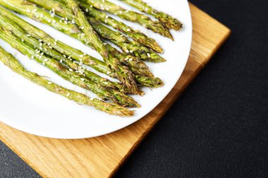 Taze ızgara kuşkonmaz mızrakları, üzerine susam tohumları serpiştirilmiş bir tabakta güzelce sıralanmış..