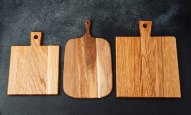 Çeşitli şekil ve boyutlarda üç tahta kesme tahtası bir arada sergileniyor..