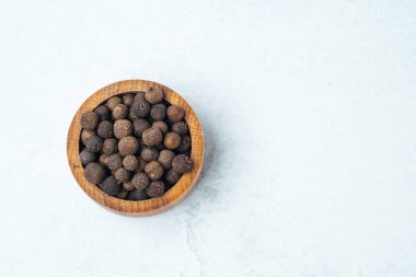 Tüm kara biber taneleri, açık mermer bir yüzeyde, ahşap bir kasede düzgünce dizilir..