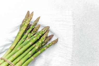 Parlak yeşil kuşkonmaz mızrakları sicimle birbirine bağlanmış temiz bir yüzeyde.