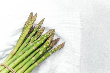 Parlak yeşil kuşkonmaz mızrakları sicimle birbirine bağlanmış temiz bir yüzeyde.