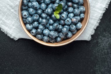 Üzerinde nane yaprağı ve keten bir bez parçasıyla kaplanmış taze yaban mersini..