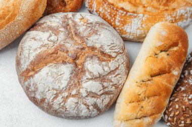 Beyaz taş bir yüzeye yerleştirilmiş çeşitli zanaatkar ekmek türleri.