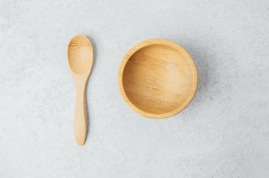 Tahta bir kâse ve eşleşen bir kaşık hafif desenli bir yüzeye konur..