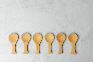 Altı ahşap kaşık düzgün dizilmiş açık gri arka planda.