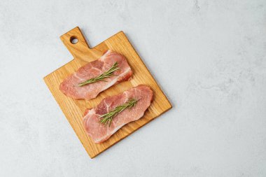 Tahtaya yerleştirilmiş taze otlarla süslenmiş iki çiğ et..