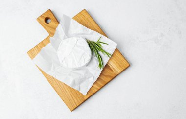 Yumuşak peynirin yuvarlak bir parçası ahşap bir kesme tahtasına konur..