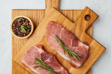 Biberiyeyle süslenmiş iki domuz pirzolası ve bir kase karışık biberli mısır..